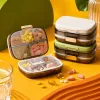 The transparent compartmented medicine box with golden fasteners contains multi-color tablets stacked beside the white and green sealed medicine box Specification image
